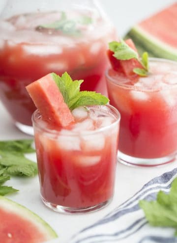 A couple glasses of watermelon agua fresca with a stick of watermelon and fresh mint.