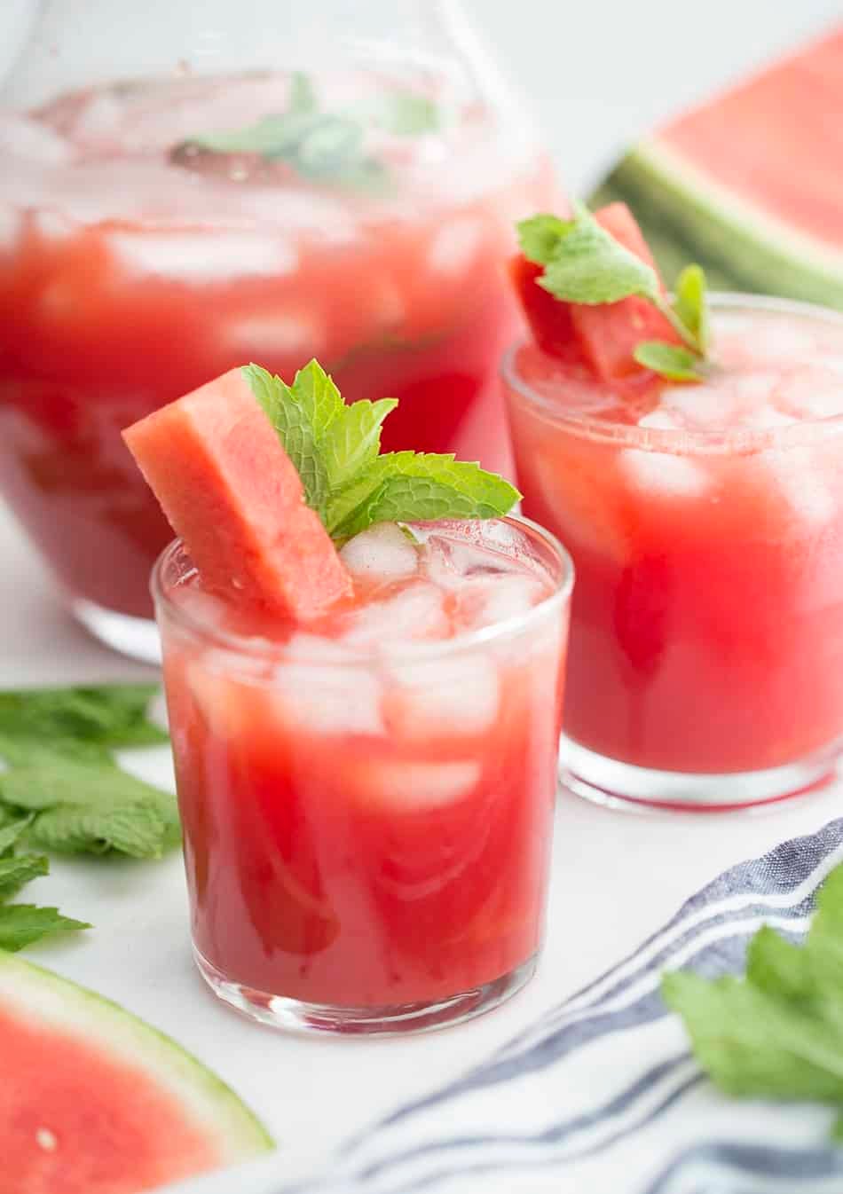 A couple glasses of watermelon agua fresca with a stick of watermelon and fresh mint.