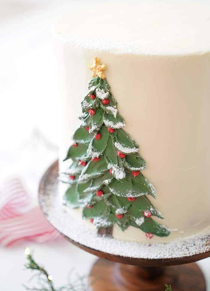 A close up photo of a buttercream Christmas tree painted onto a cake