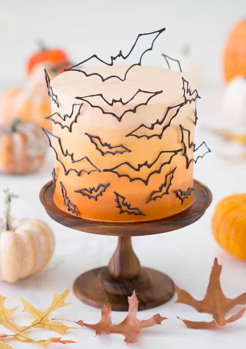 photo of an ombre orange cake covered in candy melt bats on a wooden cake stand