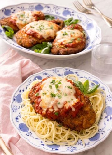 Chicken parmesan on a blue plate with spaghetti
