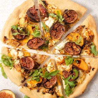 A close up of a fig pizza cut into slices