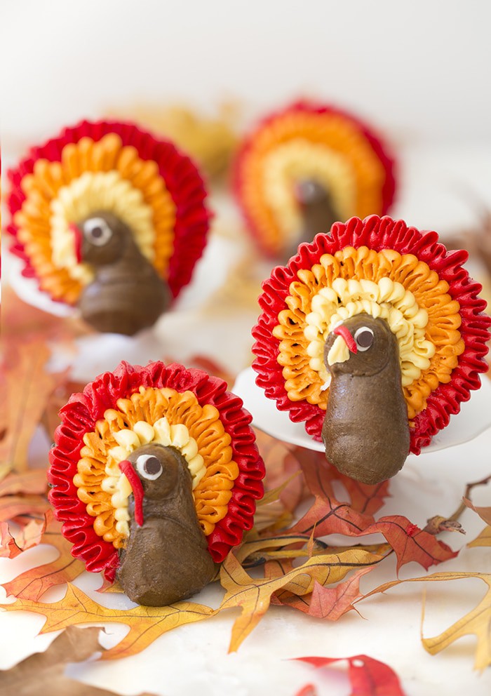 A photo of a group of cupcakes with buttercream turkeys piped onto them