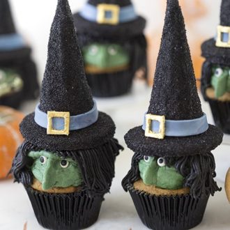 Two Halloween witch hat cupcakes with more cupcakes in the background.