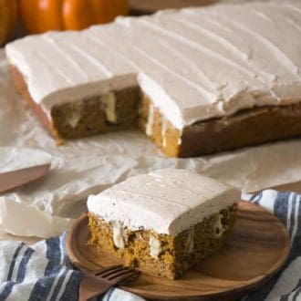 A piece of pumpkin poke cake on a wooden plate.