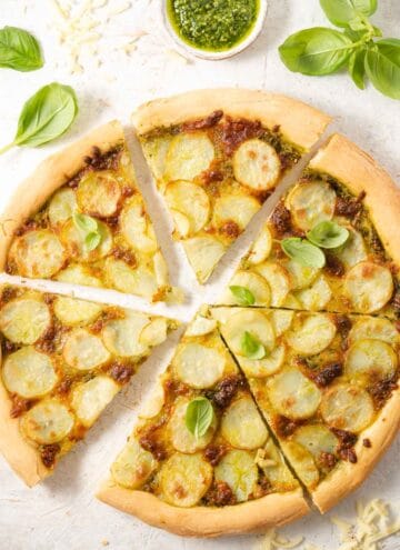 An overhead shot of a potato pizza cut into slices