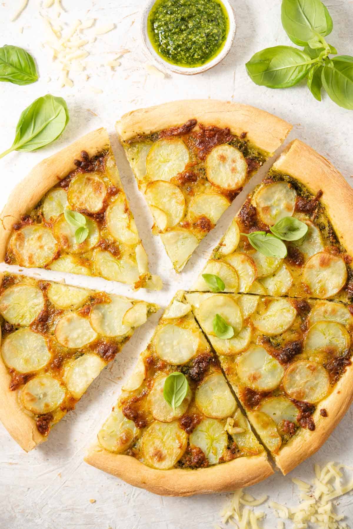 An overhead shot of a potato pizza cut into slices