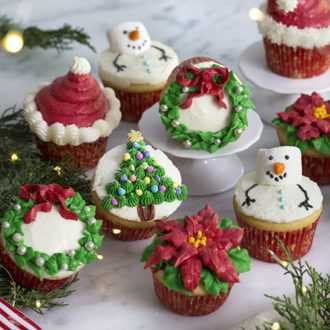 A photo of an assortment of Christmas cupcakes on a white marble table