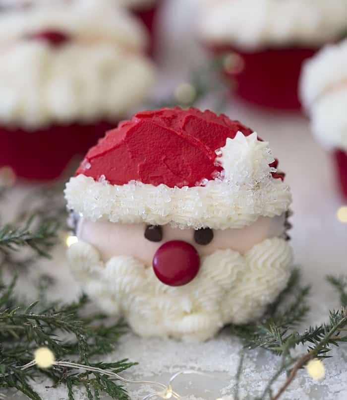 A close up phot showing a santa cupcake surrounded by Christmas lights