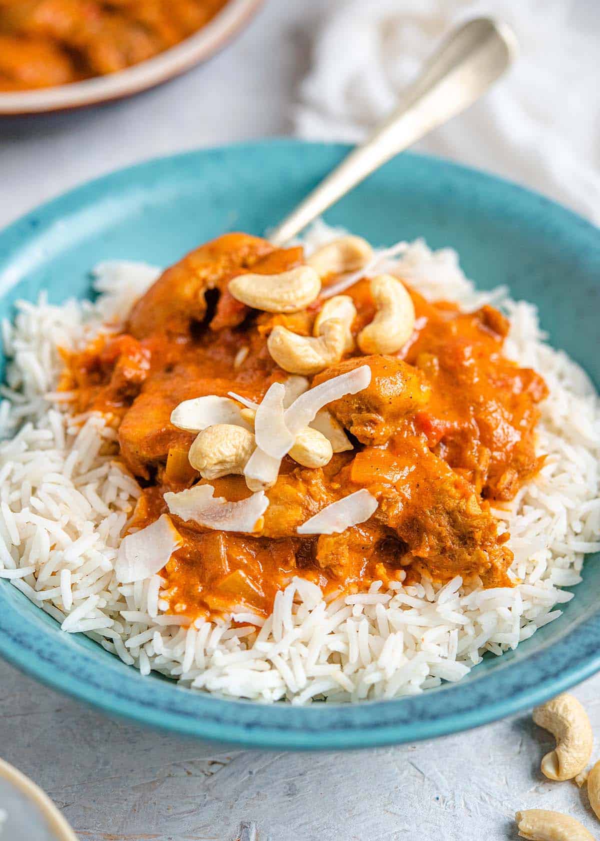 A close up of butter chicken in a bowl with rice