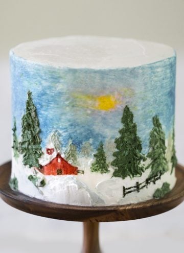 A winter barn cake on a cake stand.