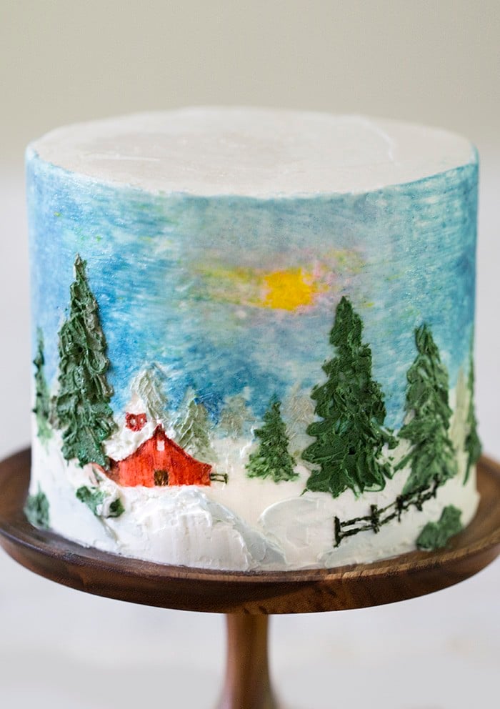 A winter barn cake on a cake stand.
