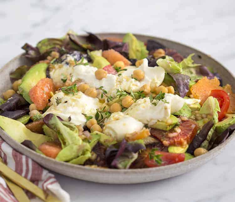 an avocado salad with chick peas and fresh thyme on a marble table