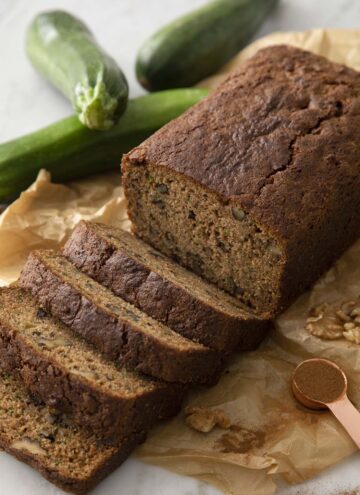 A half sliced loaf of zucchini bread on brown parchment paper.
