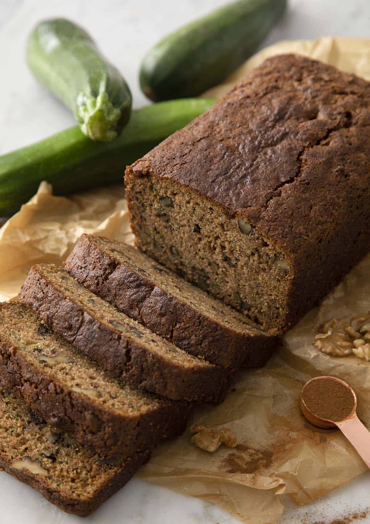 A half sliced loaf of zucchini bread on brown parchment paper.
