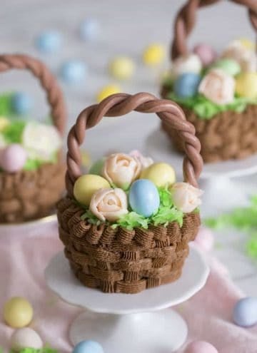 A cupcake that looks like an easter basket filled with flowers and eggs on a mini stand.