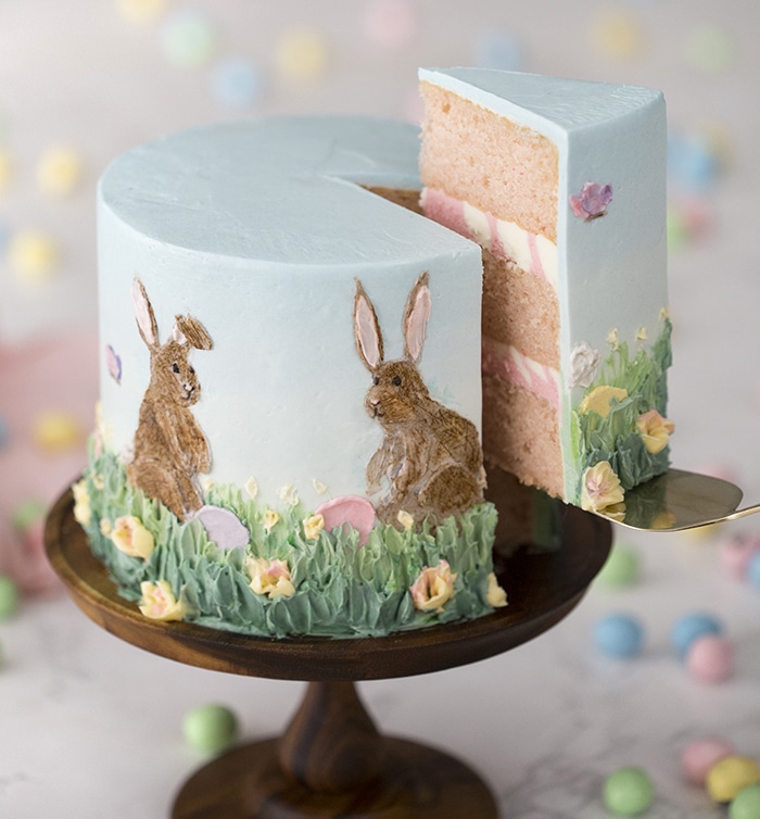 A photo of an Easter cake with a piece being removed.