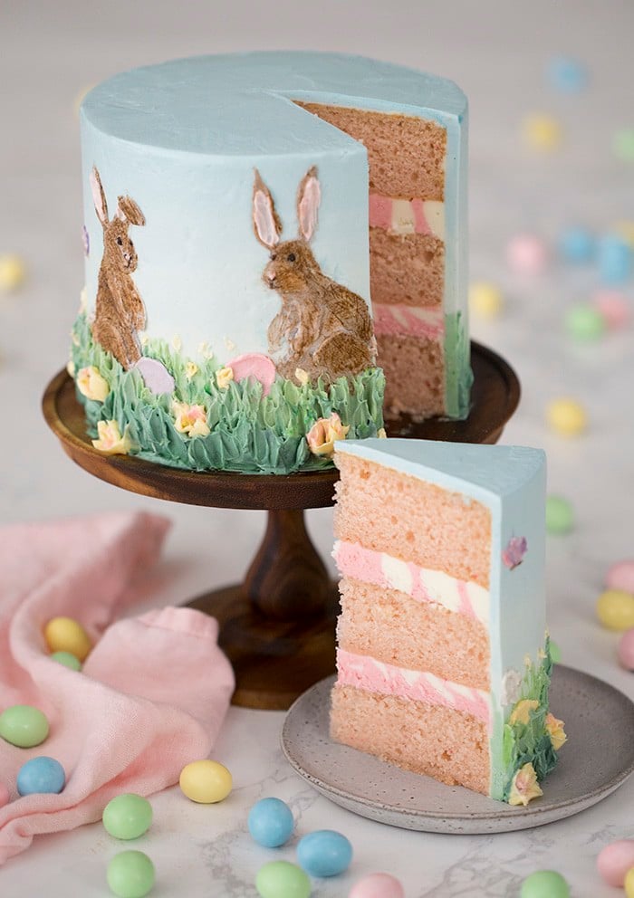 a photo showing two Easter bunnies painted in buttercream on a cake.
