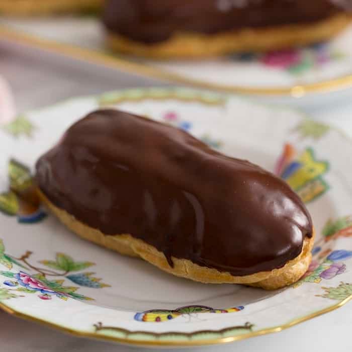 A close up photo of a chocolate eclair on a plate.