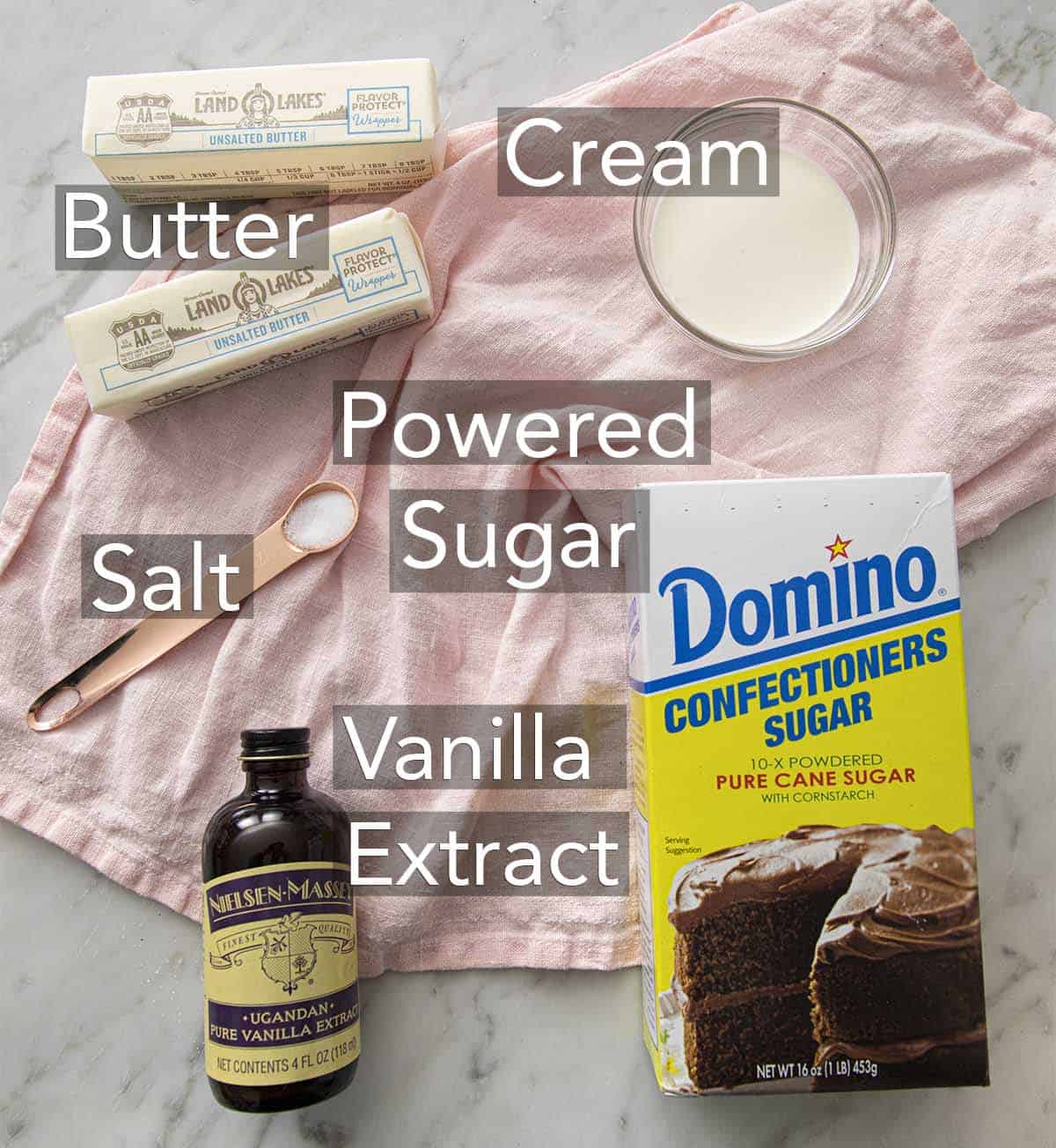 The ingredients for buttercream frosting on a marble surface.