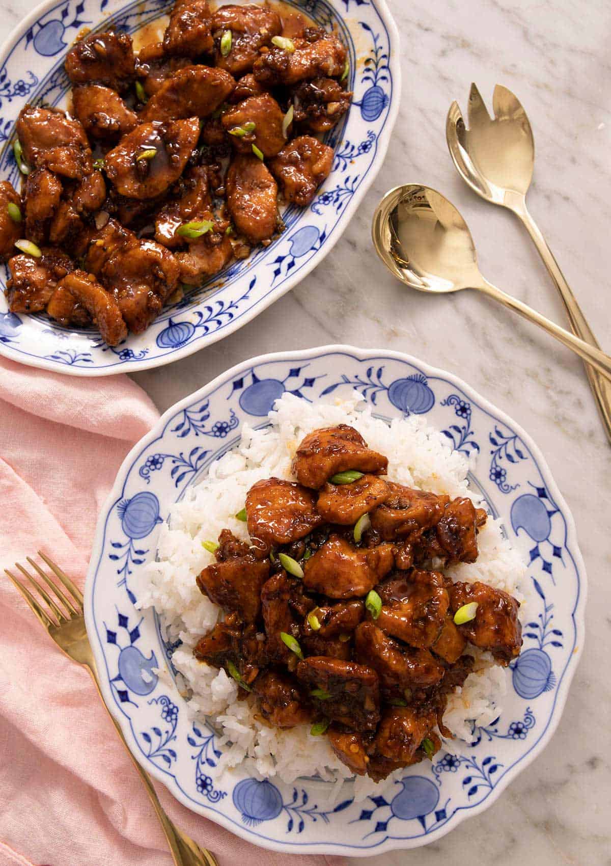 An overhead shot of Bourbon Chicken on a blue plate with rice