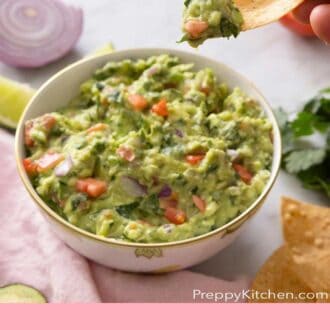 Pinterest graphic of a bowl of guacamole with a tortilla chip scooping up some.