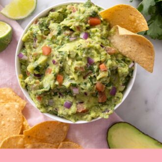 Pinterest graphic of an overhead view of a bowl of guacamole with tortilla chips. Guacamole ingredients scattered around the bowl.