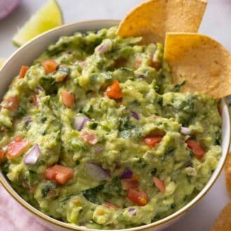 Pinterest graphic of a bowl of guacamole with two tortilla chips.