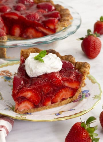 A piece of strawberry pie on a porcelain plate.