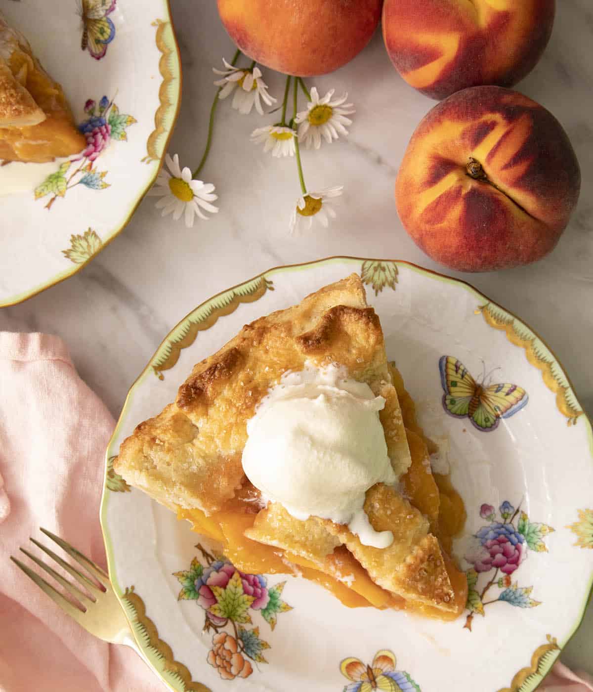 A top-down photo of a peach pie piece with melting vanilla ice cream on top.