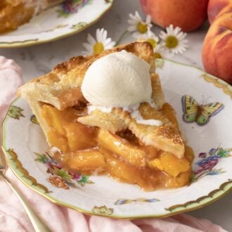 A piece of peach pie with a scoop of vanilla ice cream on top.