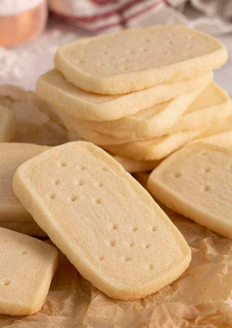 A group of shortbread cookies. some are stacked while others are on crumpled paper.