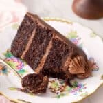 A slice of chocolate zucchini cake on a plate with a fork at the side
