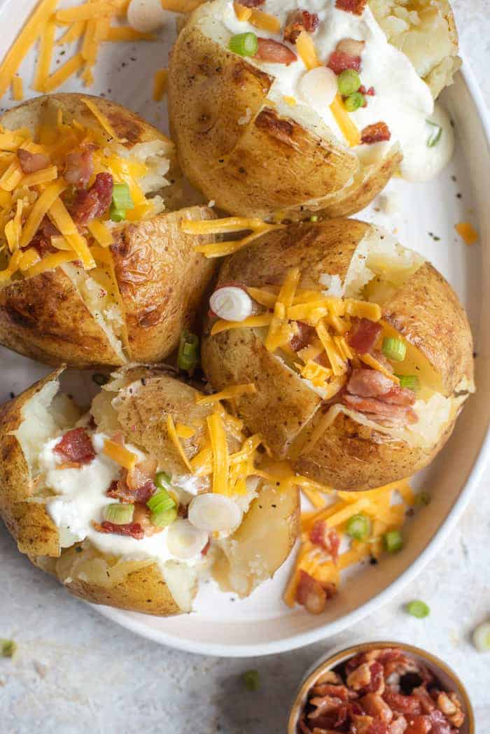 A close up of instant pot baked potatoes on a serving plate with toppings