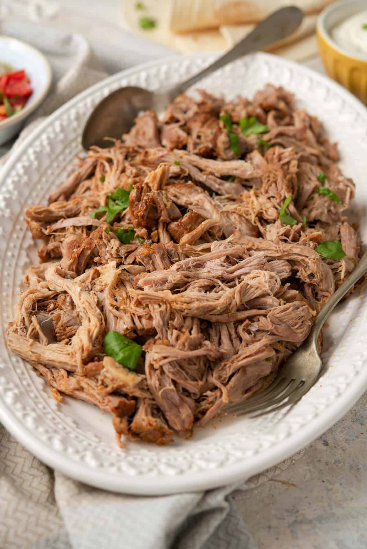 A side shot of pulled pork on a white platter