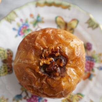 Pinterest graphic of an overhead view of a baked apple with pecans on a porcelain plate.