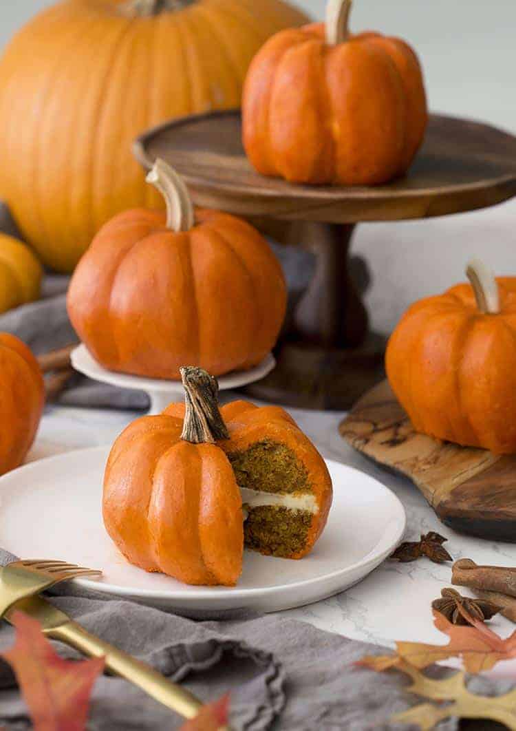 A group of small cakes that look exactly like orange pumpkins.