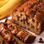 A close up view of a half sliced loaf of chocolate chip banana bread.
