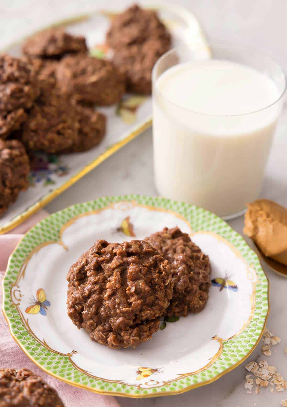 No bake cookies on a plate with a glass of milk behind it