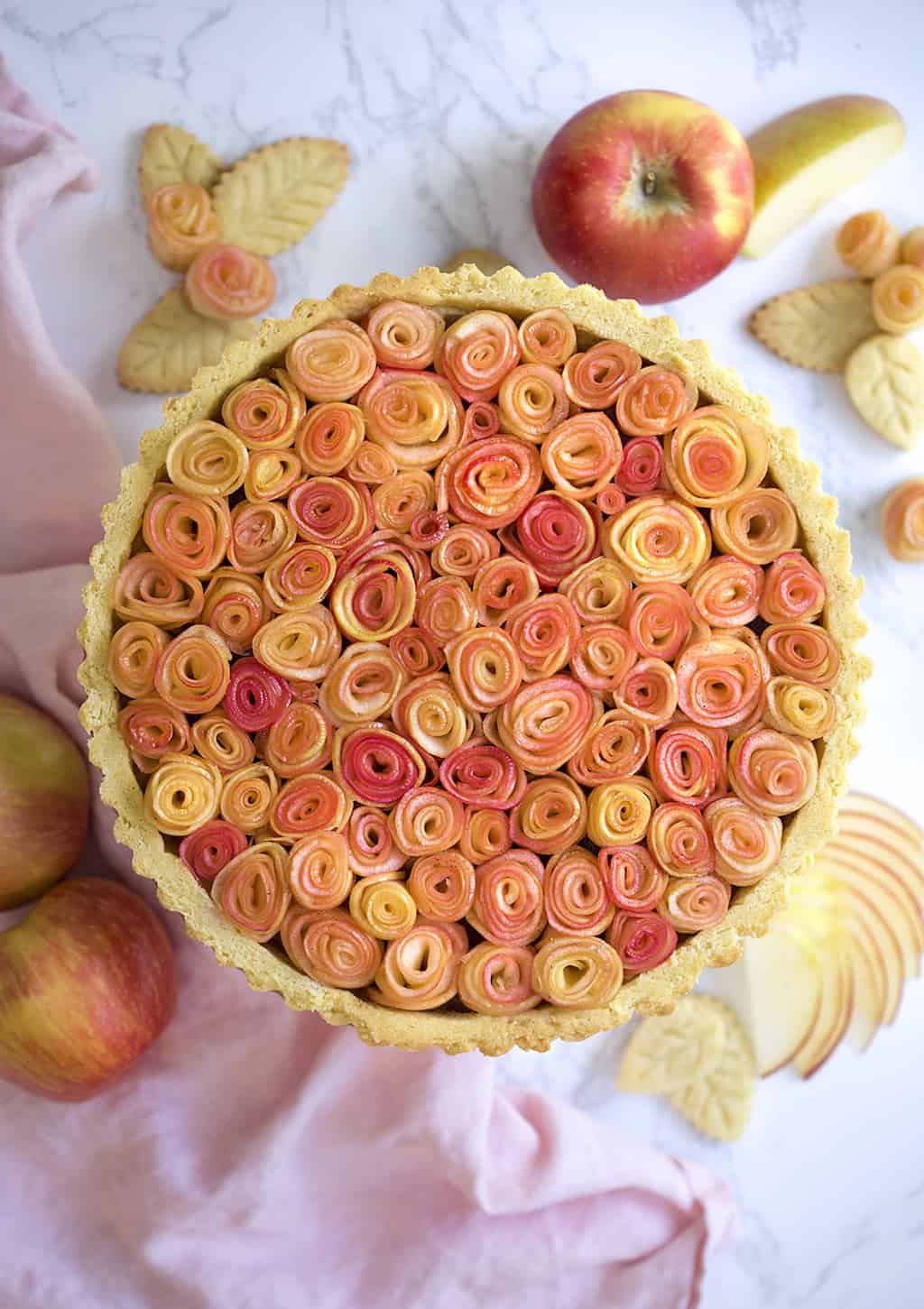 A photo of an apple rose tart on a marble table.