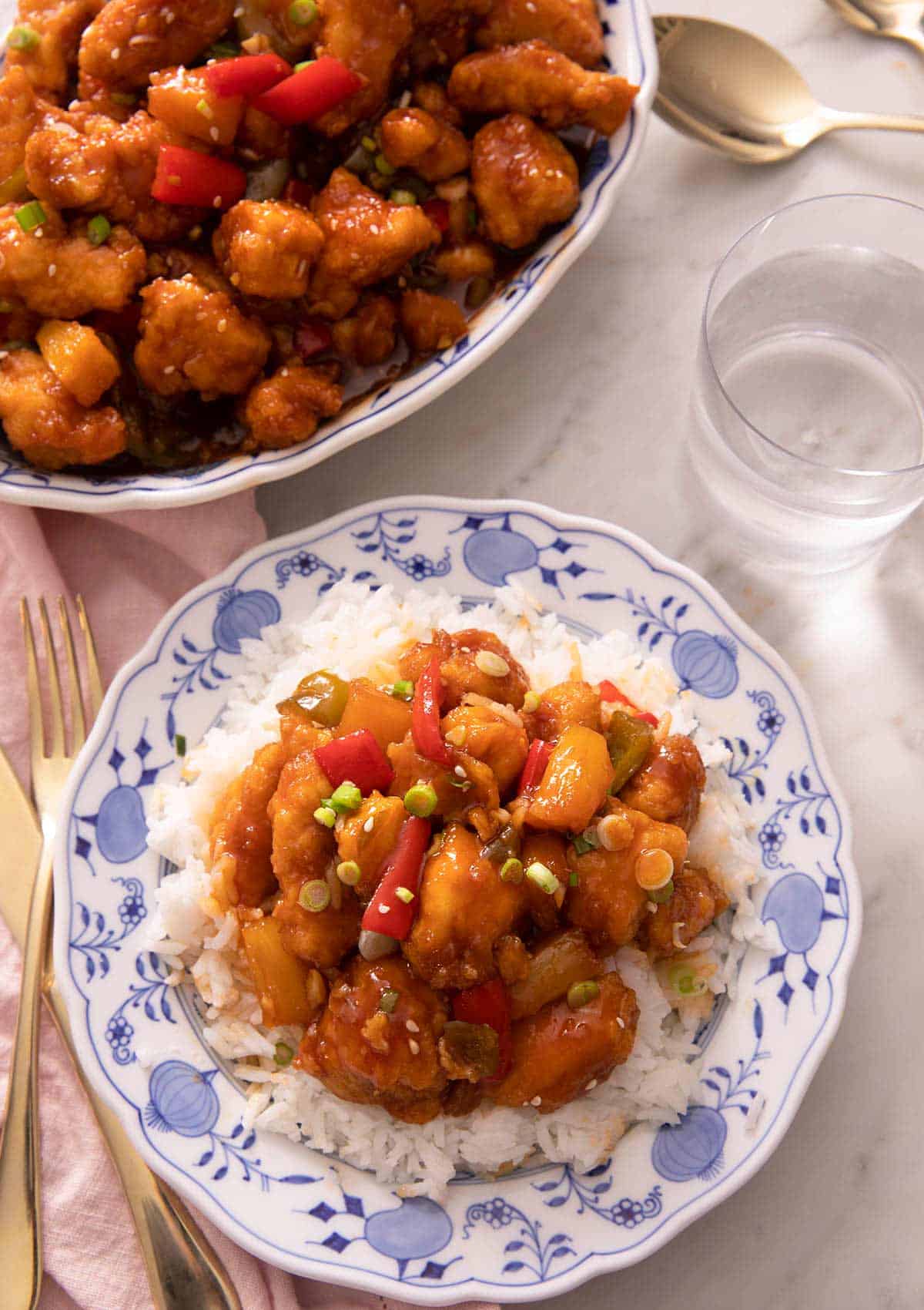 An overhead shot of sweet and sour chicken and rice on a blue plate