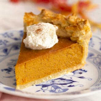 A piece of sweet potato pie on a blue and white plate.