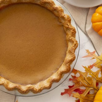 Pinterest graphic of a whole pumpkin pie in a glass pie dish.