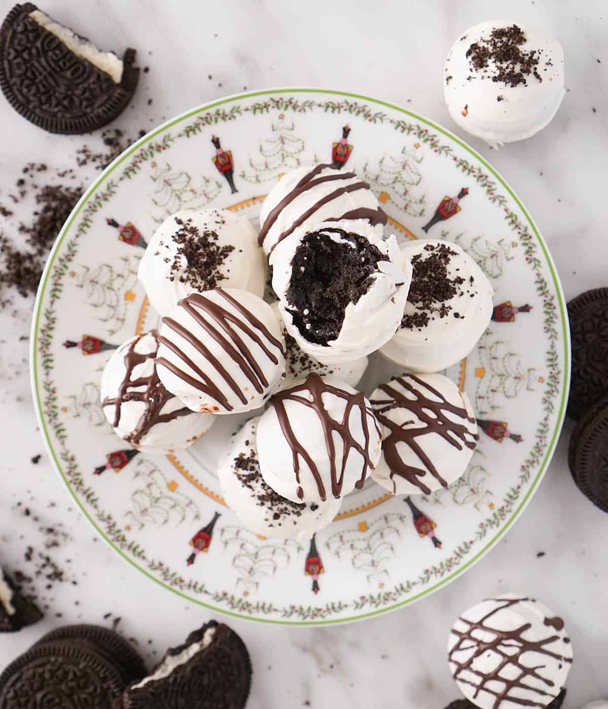 An overhead view of a plate filled with a pile of Oreo balls. Oreo cookies and balls scattered around.
