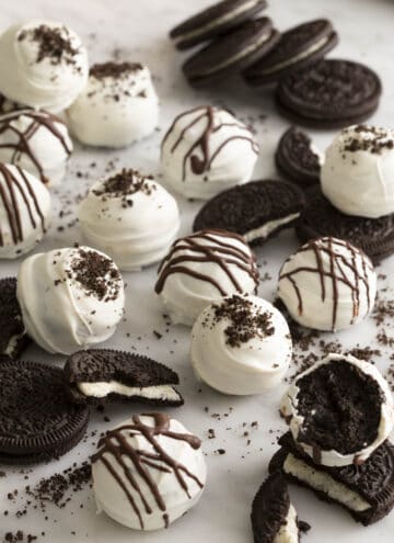 Several oreo balls and oreos scattered across a white counter.
