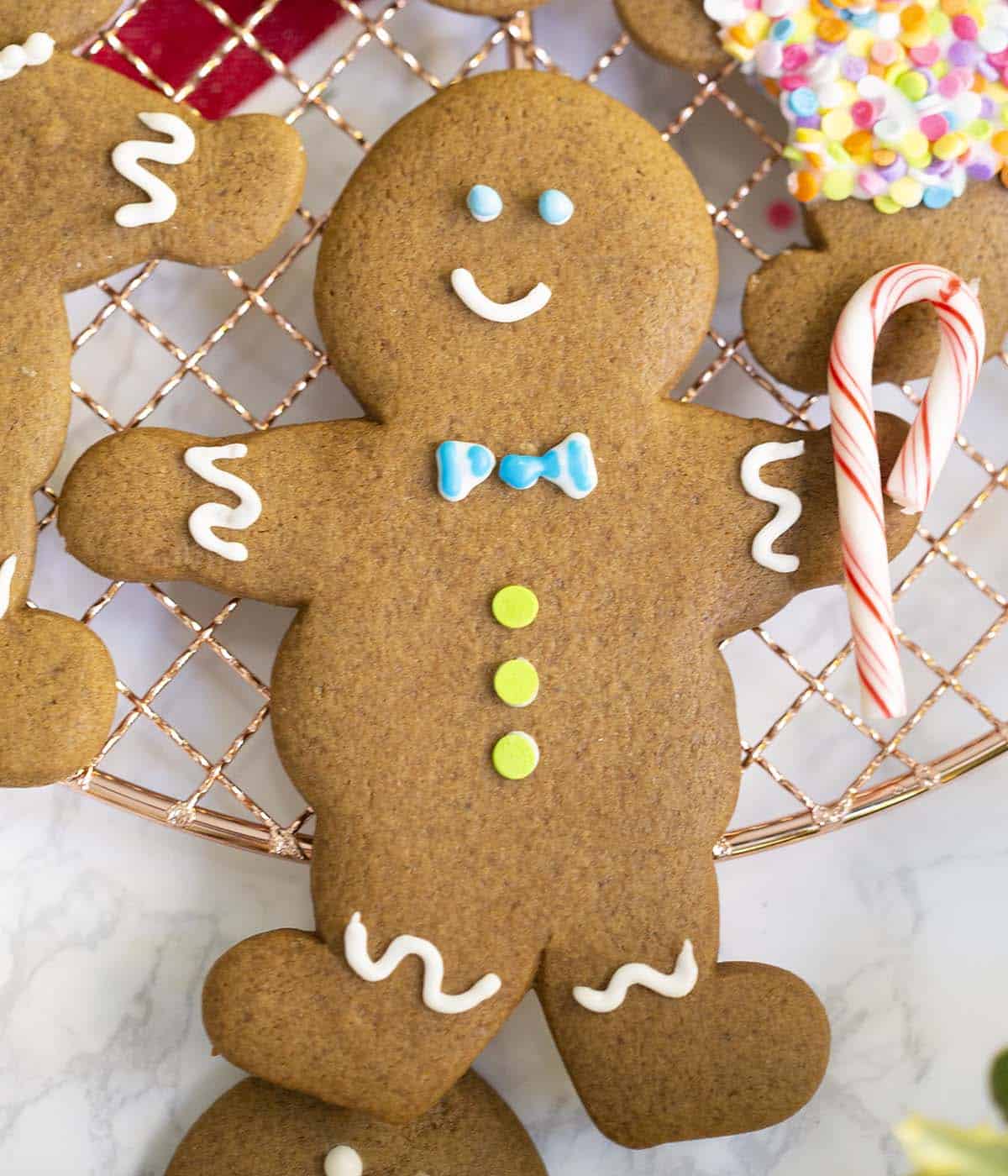 Two photos showing royal icing for gingerbread men being mixed then piped onto gingerbread cookies.