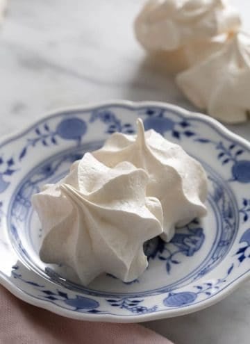 Two meringue cookies on a blue and white plate.