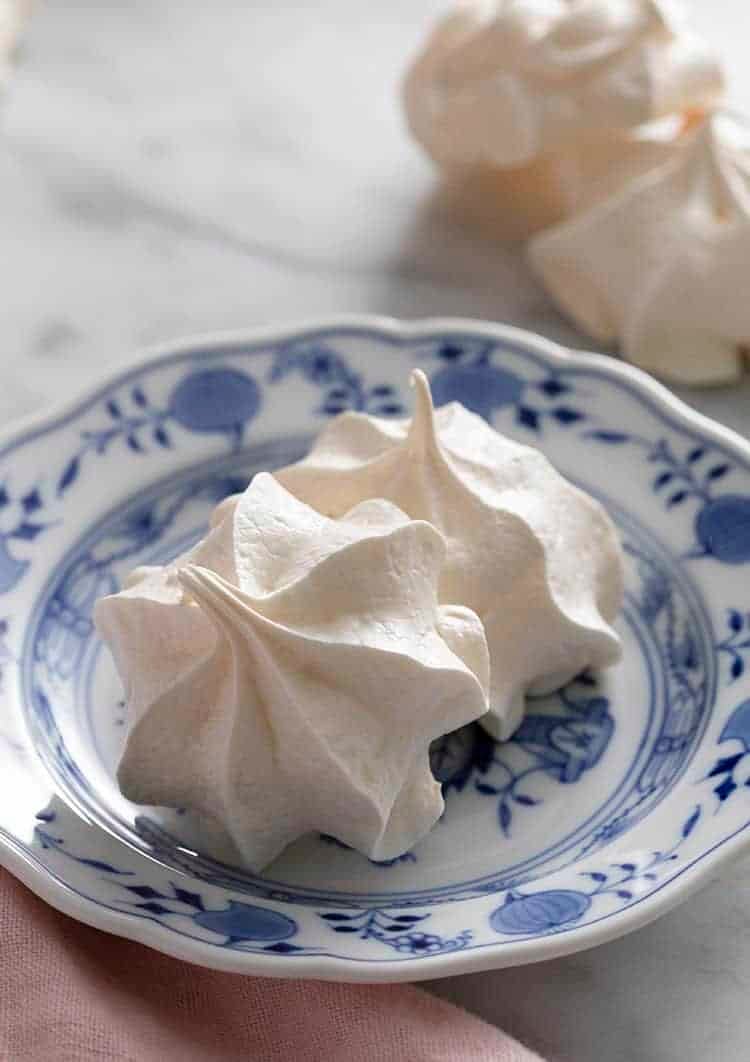 Two meringue cookies on a blue and white plate.