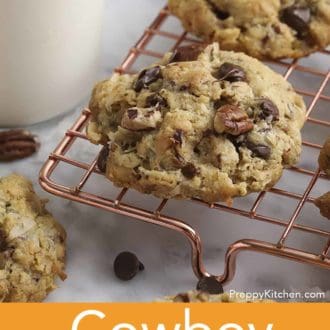 Pinterest graphic of cowboy cookies on cooling rack with a glass of milk beside it.