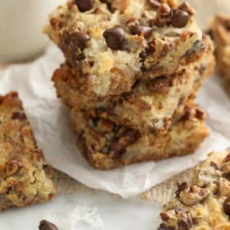 Pinterest graphic of stacked magic cookie bars on parchment paper.